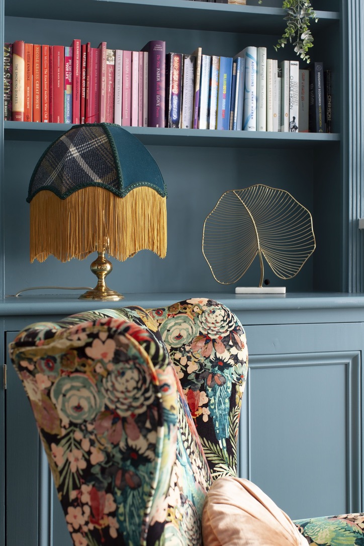 5-The-bookshelf-displays-a-vibrant-arrangement-of-colourful-books-complemented-by-a-quirky-lamp-with-a-fringed-shade-and-a-golden-decorative-accent.-