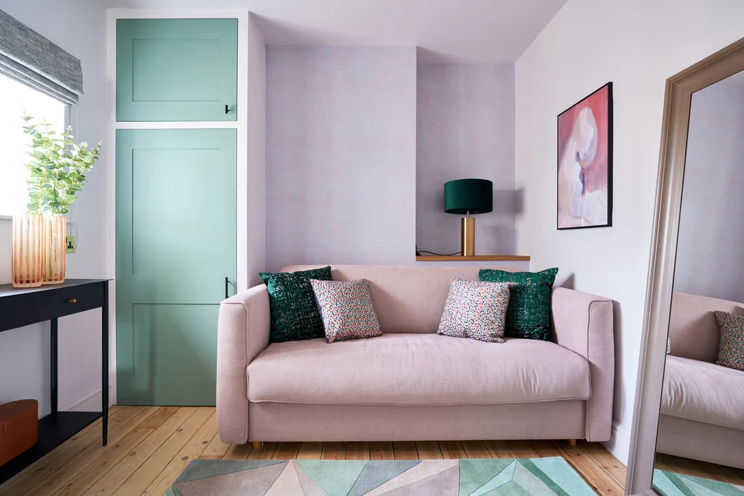 Home transformation a cosy and colourful living space with lilac walls and sage green built in cabinets, finished off with a blush pink sofa and teal cushions.
