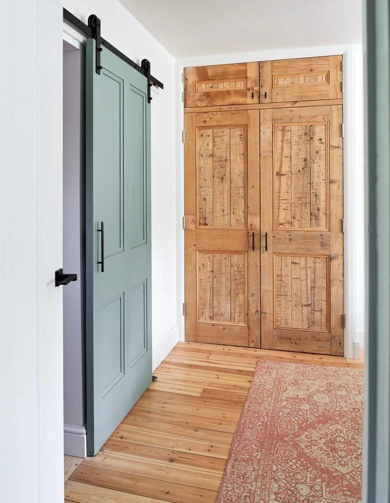 Home transformation a bright and airy hall way leads into the bedroom with a sage green sliding door and rust patterned rug upon the original wooden flooring.