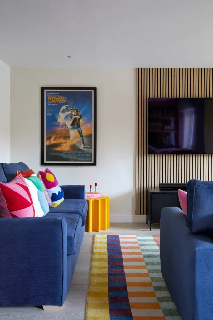 Interior Designer in Ascot vibrant cushions on navy sofas pick up the colours from the Back to the Future Poster on the wall