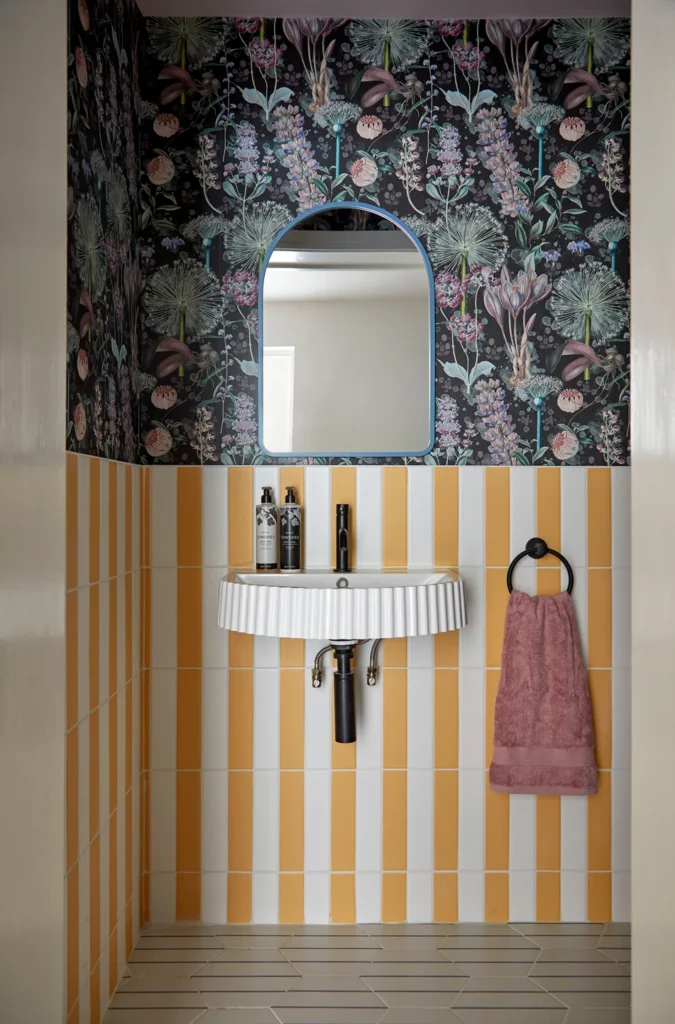 A Chiswick interior designer created this feature yellow striped bathroom wall paper with contrast dark navy floral paper above the sink