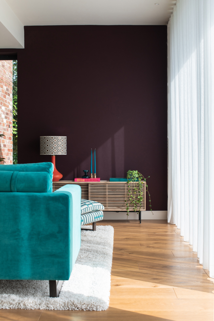 Kate Lovejoy Interiors A close up of a console table with vibrant decorations on it and a teal sofa.