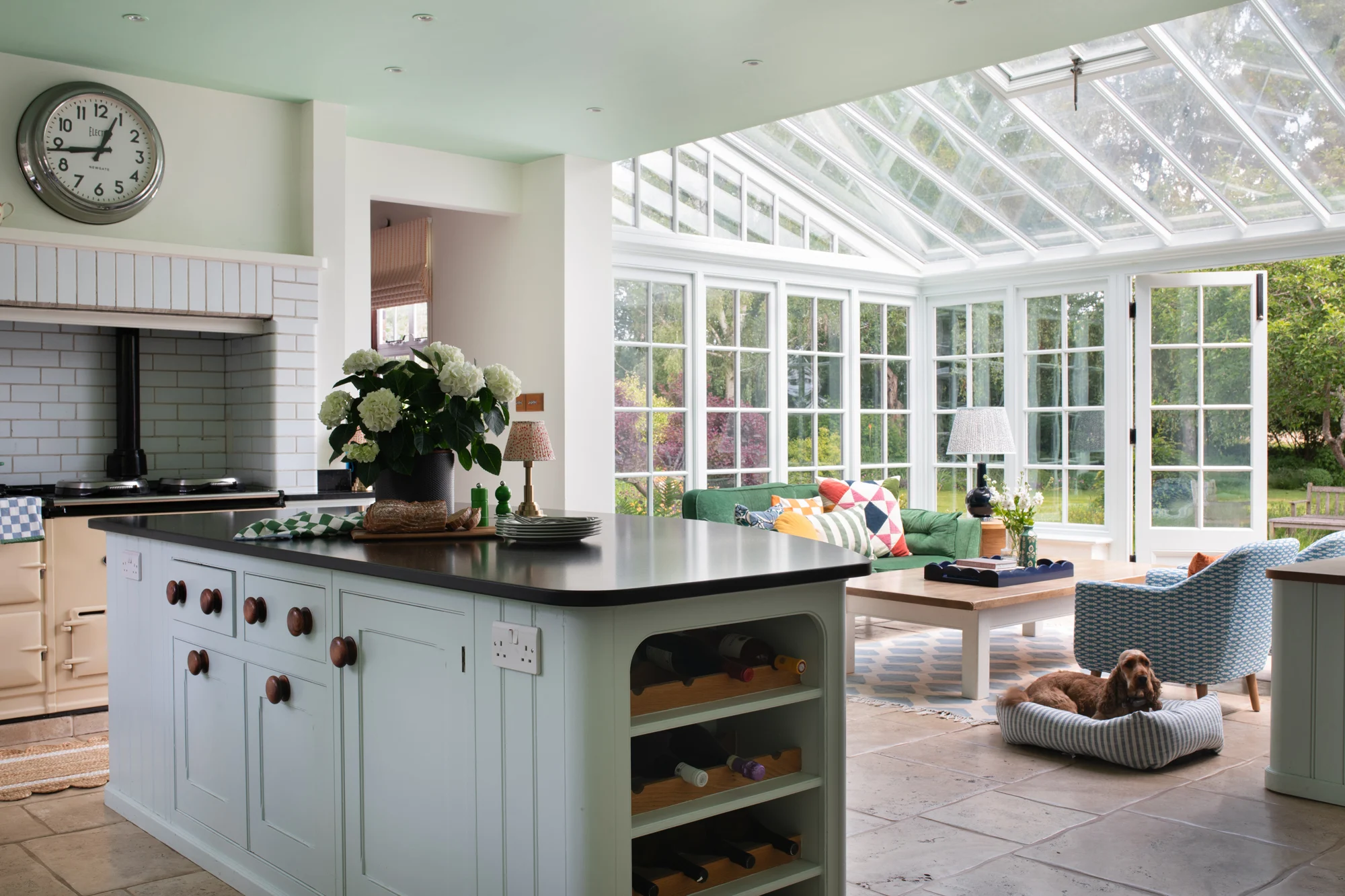 Garden‑inspired interior design kitchen-diner with hand-painted floral cabinetry, organic dining table, woven accents, and fresh indoor plants.