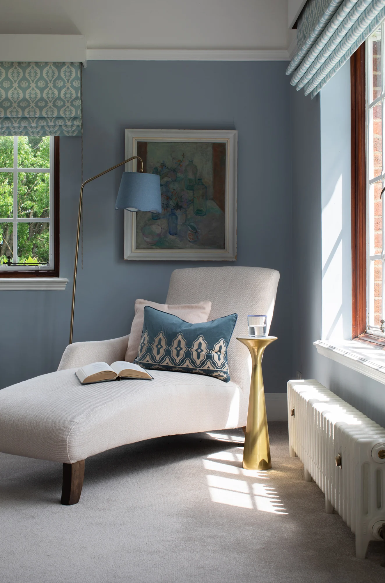 Garden‑inspired interior design reading nook with velvet armchair, leafy wallpaper backdrop, and a side table adorned with a plant.