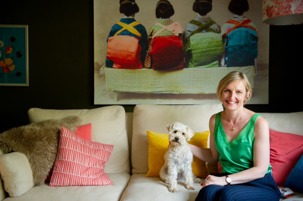 Kate with her white dog on a cream couch with colourful cushions - the face behind Home by Kate Lovejoy interiors