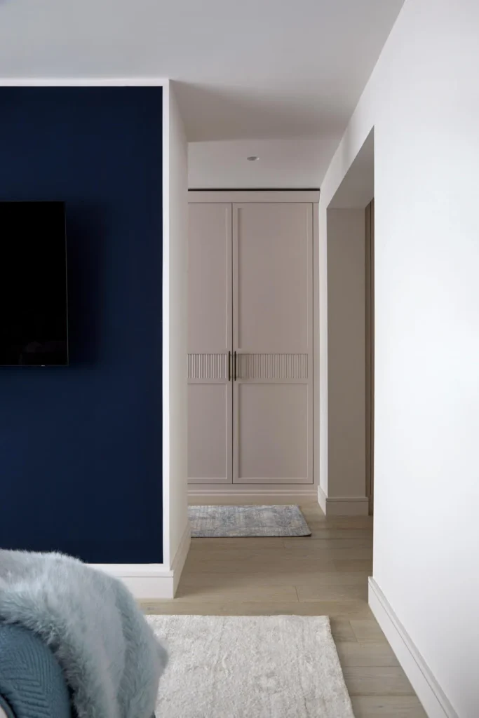 Renovating your home: bespoke light pink wardrobes set against rich navy blue walls for a bold yet elegant bedroom transformation.