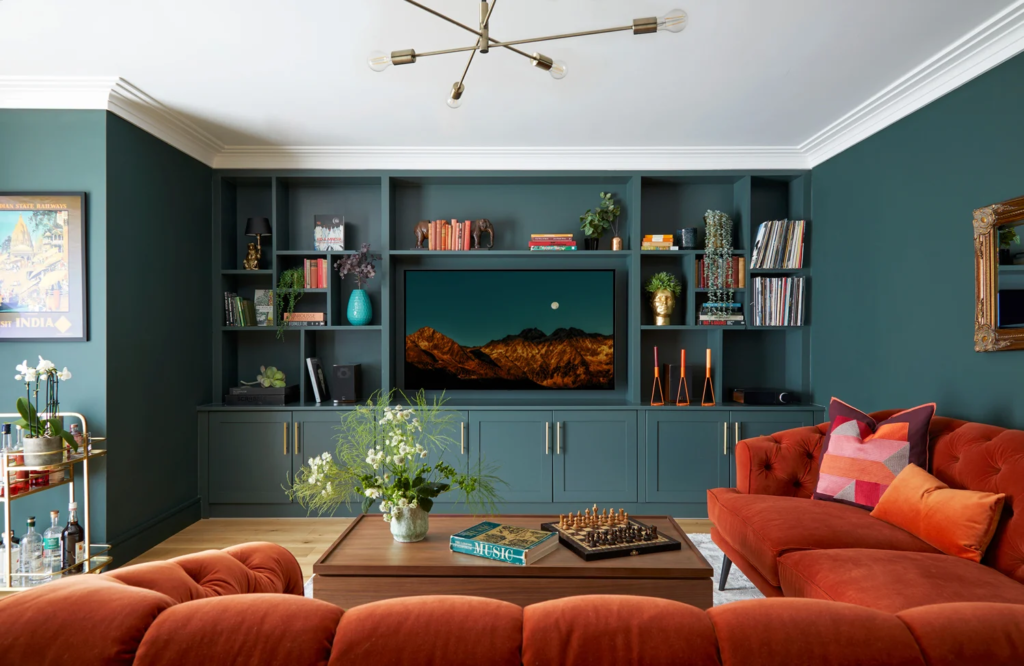 Cosy and sophisticated living room with deep green walls, burnt orange sofa, and bespoke joinery.