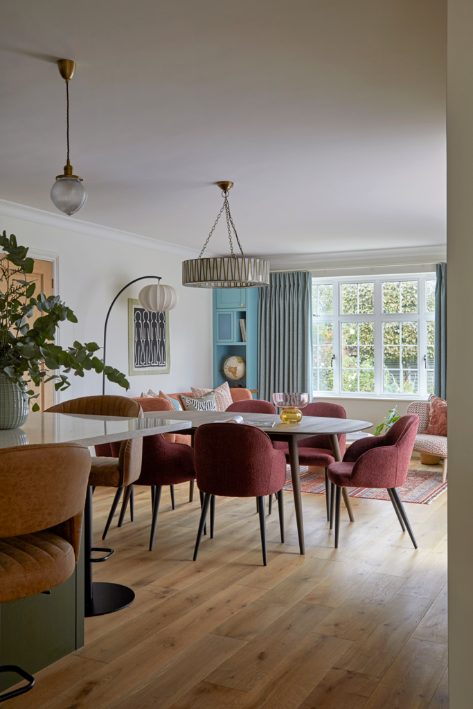 Completed open plan dining and kitchen space from Kate Lovejoy Interiors Feasibility and Space Planning Consultation, featuring red velvet chairs, oak flooring and blue cabinetry.