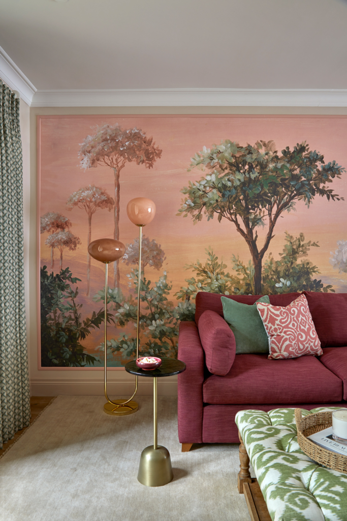Cosy snug area designed by Kate Lovejoy Interiors in Maidenhead, featuring plum red sofa with textured cushions, statement lighting and a landscape backdrop.