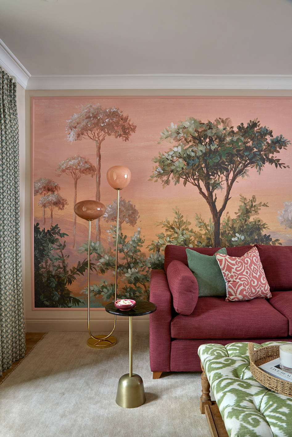 Cosy snug area designed by Kate Lovejoy Interiors in Maidenhead, featuring plum red sofa with textured cushions, statement lighting and a landscape backdrop.