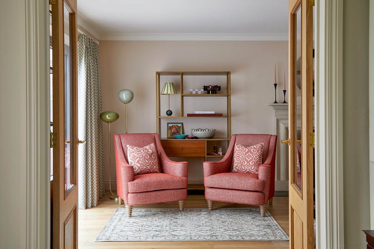 transformed family home by kate lovejoy interiors shows an open plan hallway with a neutral colour scheme, terracotta armchairs, textured cushions and statement lighting