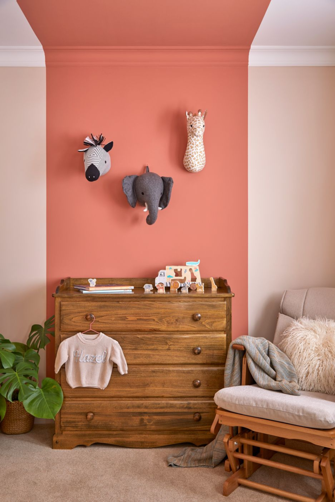 this nursery in a transformed family home by kate lovejoy interiors has tones of peach and terracotta with an oak chest of drawers and animal detailling on the wall